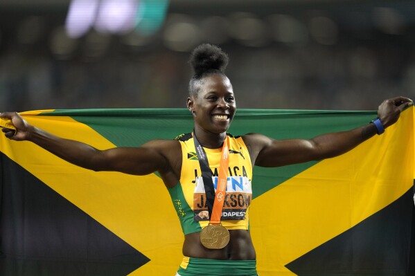 Shericka Jackson, center, of Jamaica, poses after winning the women's 200-meters final during the World Athletics Championships in Budapest, Hungary, Friday, Aug. 25, 2023. (AP Photo/Ashley Landis)