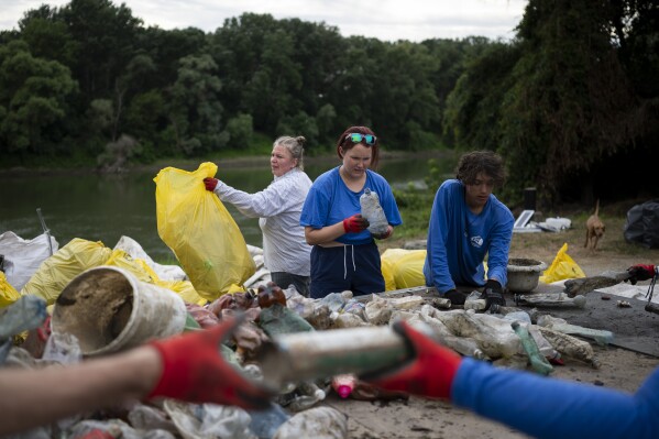 Volunteers sort the collected rubbish after they arrived at a campsite on Tuesday, Aug. 1, 2023. Since its start in 2013, participants in the annual Plastic Cup competition — which offers a prize for those who collect the most trash each year — have gathered more than 330 tons (around 727,000 pounds) of waste from the Tisza River and other Hungarian waters. (AP Photo/Denes Erdos)