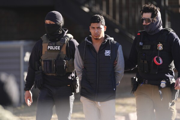 Law officials escort a suspect from an apartment to a waiting utility vehicle for transport during a raid Wednesday, Feb. 5, 2025, in east Denver. (AP Photo/David Zalubowski, File)