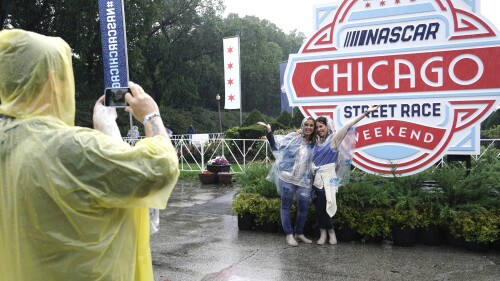 Fans take pictures in the rain before a NASCAR Cup Series auto race at the Grant Park 220 Sunday, July 2, 2023, in Chicago. (AP Photo/Morry Gash)