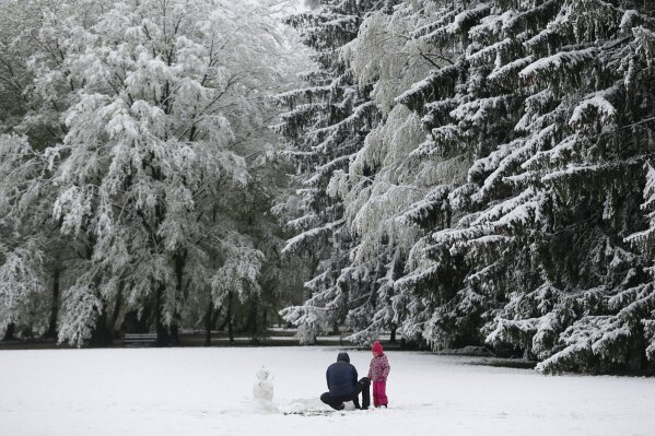 A child and an adult make a snowman in a park after a snowfall,  in Zagreb, Croatia, Tuesday, April 6, 2021. (AP Photo/Darko Bandic)