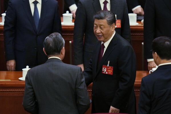 Chủ tịch Trung Quốc Tập Cận Bình, phải, trò chuyện với Bộ trưởng Ngoại giao Vương Nghị khi ông rời đi sau phiên khai mạc Đại hội Đại biểu Nhân dân Toàn quốc (NPC) tại Đại lễ đường Nhân dân ở Bắc Kinh, Trung Quốc, Thứ Ba, ngày 5 tháng 3 năm 2024. (Ảnh AP) /Ngô Hán Quan)