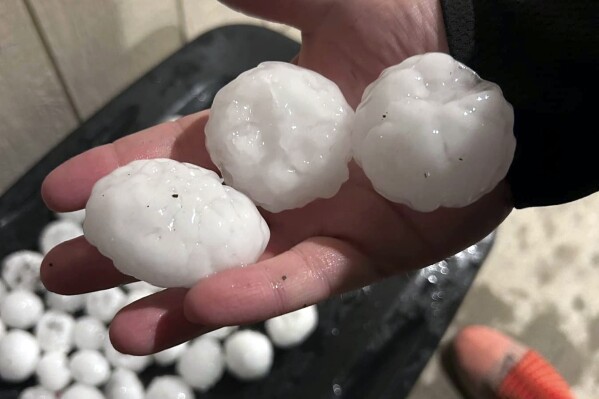 In this image provided by Jeremy Crabtree, large chunks of hail are shown, Wednesday night, March 13, 2024, in Shawnee, Kan. Volatile weather was honing in on parts of Kansas and Missouri Wednesday night, with some storms bringing massive chunks of hail. (Jeremy Crabtree via AP)