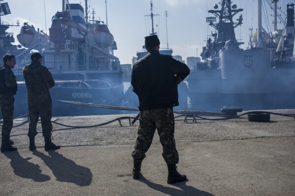 FILE - Men in unmarked uniforms stand guard during the seizure of the Ukrainian corvette Khmelnitsky in Sevastopol, Crimea, Thursday, March 20, 2014. When Ukraine's Kremlin-friendly president was ousted in 2014 by mass protests that Moscow called a U.S.-instigated coup, Russian President Vladimir Putin responded by sending troops to overrun Crimea and staging a plebiscite on joining Russia, which the West dismissed as illegal. (AP Photo, File)