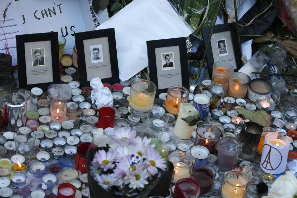FILE - In this Nov.15, 2015 file photo, pictures of victims are placed behind candles outside the Bataclan concert hall in Paris.For more than two weeks, dozens of survivors from the Bataclan concert hall in Paris have testified in a specially designed courtroom about the Islamic State’s attacks on Nov. 13, 2015 – the deadliest in modern France. The testimony marks the first time many survivors are describing – and learning – what exactly happened that night at the Bataclan, filling in the pieces of a puzzle that is taking shape as they speak. (AP Photo/Christophe Ena, File)