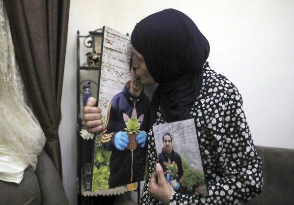 FILE - In this June 3, 2020 file photo, Rana kisses a photo of her son, Eyad Hallaq, in their home in Wadi Joz, a Palestinian neighborhood in East Jerusalem. On Wednesday, Oct. 21, 2020, Israeli prosecutors recommended charging a police officer with reckless killing in the fatal shooting of Hallaq, an autistic Palestinian man in Jerusalem’s Old City earlier this year. The decision came nearly five months after the shooting and Hallaq’s family condemned the decision saying police should have faced much tougher charges. (AP Photo/Mahmoud Illean, File)