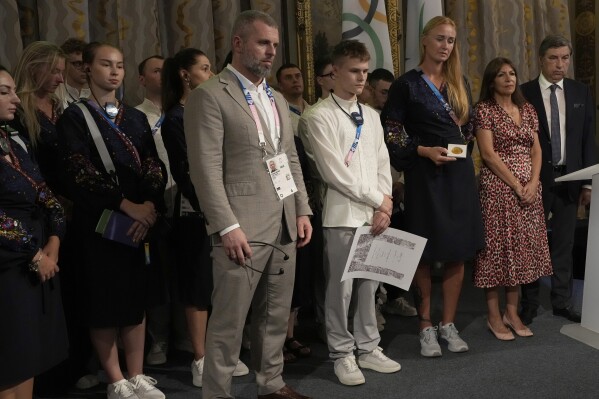 Paris mayor Anne Hidalgo, second right, Ukrainian athletes Oleskii Sereda, fourth right, Anastasiia Kozhenkova, third right, Ukrainian Sports Minister Matuii Bidnyi and other athletes observe a minute of silence, during a ceremony at the 2024 Summer Olympics, Thursday, Aug. 1, 2024, in Paris, France. Hidalgo awarded the whole Ukrainian delegation.with the Medal of the City of Paris. (AP Photo/Michel Euler)