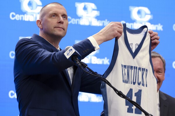 Mark Pope holds up his old playing jersey to fans and media after being named Kentucky men's NCAA college basketball head coach in Lexington, Ky., Sunday, April 14, 2024. (AP Photo/James Crisp)
