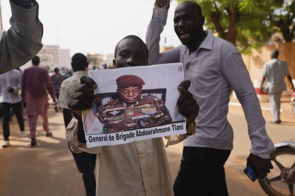 FILE - Nigeriens participate in a march called by supporters of coup leader Gen. Abdourahmane Tchiani, pictured, in Niamey, Niger, July 30, 2023. Niger鈥檚 junta has signed a decree revoking a 2015 law that was enacted to curb the smuggling of migrants traveling from African countries through a key migration route in Niger en route to Europe, according to a government circular issued on Monday, Nov. 27. 鈥淭he convictions pronounced pursuant to said law and their effects shall be cancelled,鈥� Tchiani, said in a Nov. 25 decree, a copy of which was seen Monday by 花椒直播. (AP Photo/Sam Mednick, File)