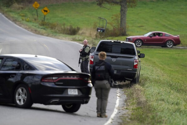FILE - Law enforcement officers hold rifles while investigating a scene, in Bowdoin, Maine, Thursday, Oct. 26, 2023. On Friday, Oct. 27, The Associated Press reported on stories circulating online incorrectly claiming an aerial video of a man lying on his stomach in the middle of a road, being detained by authorities, shows police arresting Maine shooting suspect Robert Card. (AP Photo/Steven Senne, File)