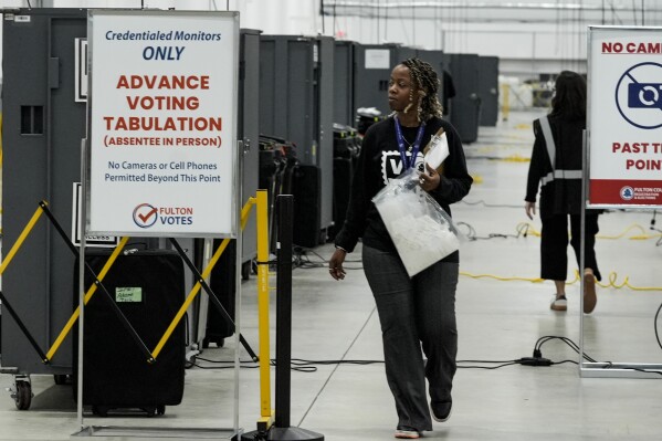 An election worker walks near voting machines at the Fulton County Election Hub and Operation Center, Nov. 5, 2024, in Atlanta. (AP Photo/John Bazemore, File)