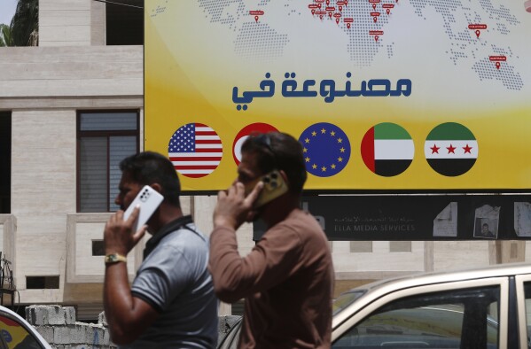 Syrian men speak on their phones on a street in Damascus, Syria, Wednesday, May 14, 2025. (AP Photo/Omar Sanadiki)