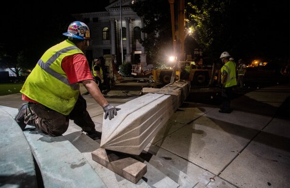 Workers secure a Confederate monument with straps after removing it from its base Thursday, June 18, 2020, in Decatur, Ga. The 30-foot obelisk in Decatur Square, erected by the United Daughters of the Confederacy in 1908, was ordered by a judge to be removed and placed into storage indefinitely. (AP Photo/Ron Harris)
