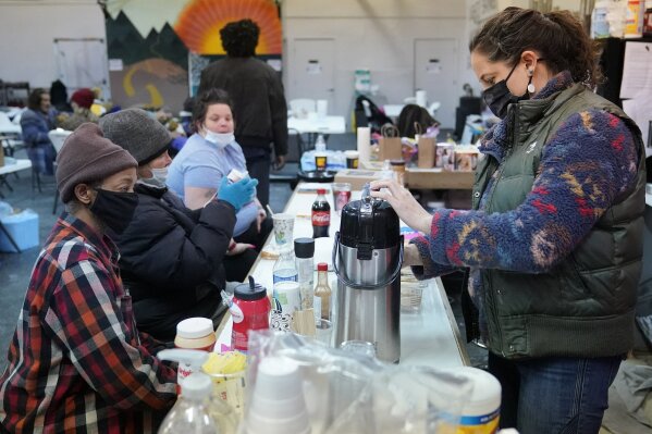 Kendra Clements, right, prepares coffee for, from left, Ruddy, Brenda and Crystal, Wednesday, Feb. 17, 2021, at the gym cafe at Tribe Gym, which has been turned into a temporary homeless shelter, in Oklahoma City. Clements and her partner Tiffany Whisman, who owns Tribe Gym, are two of several businesspeople who have opened their businesses as shelters for the homeless or people without heating during the recent severe winter weather. (AP Photo/Sue Ogrocki)