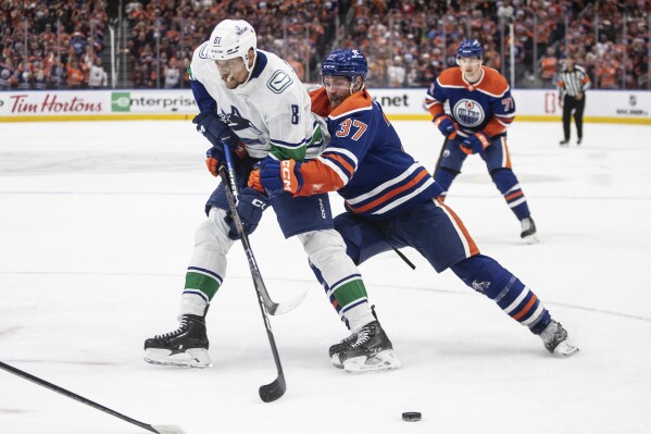 Vancouver Canucks' Dakota Joshua (81) is defended by Edmonton Oilers' Warren Foegele (37) during the third period of Game 6 of an NHL hockey Stanley Cup second-round playoff series, Saturday, May 18, 2024, in Edmonton, Alberta. (Jason Franson/The Canadian Press via AP)