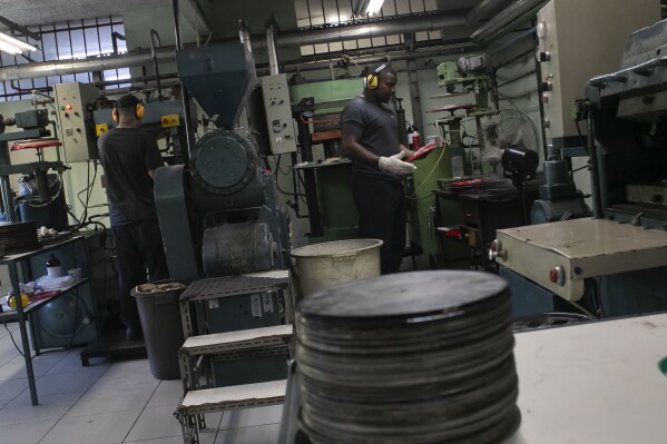 Operators work in the pressing stage of vinyl records production at the Polysom factory in Belford Roxo, Brazil, Tuesday, April 16, 2024. Vinyl’s comeback in Brazil follows a global trend over the last 15 years. In the U.S. alone, revenues from vinyl records hit .4 billion in 2023, according to the Recording Industry Association of America. (AP Photo/Bruna Prado)