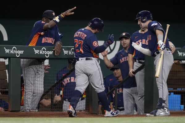 Houston Astros' Jose Altuve (27) celebrates with manager Dusty Baker Jr., left, Alex Bregman, right, and the rest of the team after hitting a solo home run in the second inning of a baseball game against the Texas Rangers, Tuesday, Sept. 5, 2023, in Arlington, Texas. (AP Photo/Tony Gutierrez)