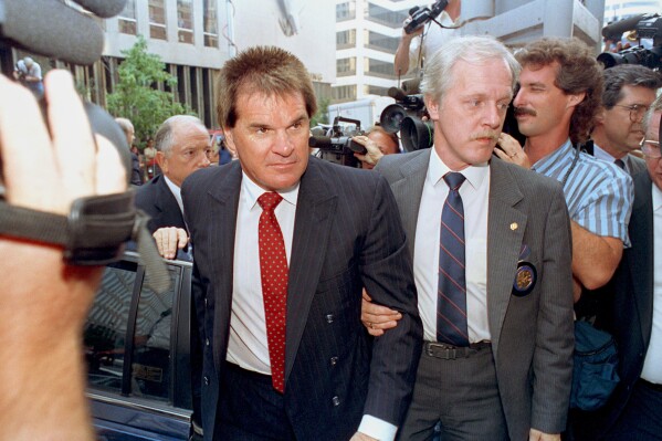 Former Cincinnati Reds manager Pete Rose is escorted by a Federal Marshal, right, as he arrives at federal court in Cincinnati, Ohio on July 19, 1990. (AP Photo/Mark Lyons, File)
