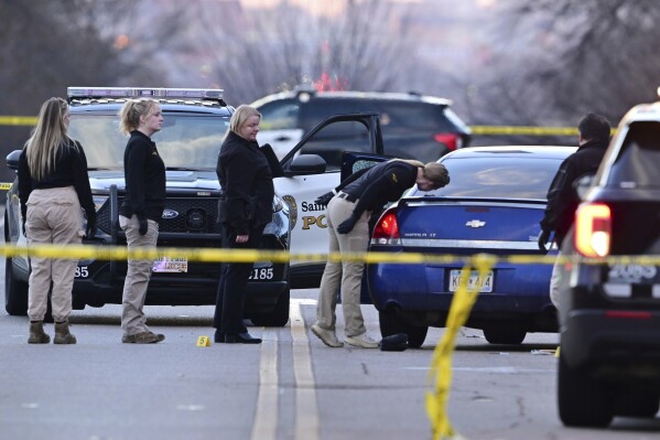 FILE - Investigators examine a car with a broken door window at the scene where a St. Paul police officer was wounded in the leg in an exchange of gunfire with a suspect at the intersection of Cretin and Marshall Ave. in St. Paul, Minn. on Thursday, Dec. 7, 2023. A St. Paul police officer was justified when he fatally shot a man who shot him first, prosecutors announced Thursday, May 30, 2024. (John Autey/Pioneer Press via AP, File)