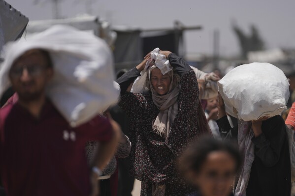 Palestinians carry bags containing food and humanitarian aid packages delivered by the Gaza Humanitarian Foundation, a U.S.-backed organization, in Rafah, southern Gaza Strip, Monday, June 16, 2025. (AP Photo/Abdel Kareem Hana)