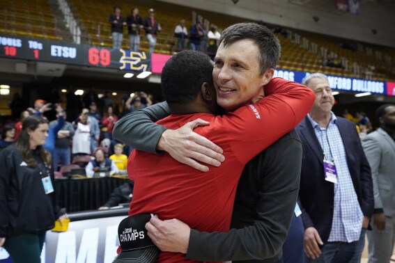FILE - Samford head coach Bucky McMillan is hugged by assistant coach Lorenzo Jenkins after their team won the NCAA men"s college basketball championship game for the Southern Conference tournament against East Tennessee State, March 11, 2024, in Asheville, N.C. Samford coach Bucky McMillan has led his hometown team to its first NCAA Tournament in 24 years. (AP Photo/Kathy Kmonicek, File)