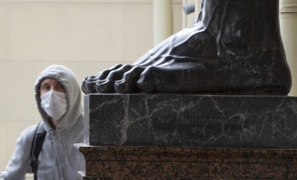 A man wearing a face mask to protect against coronavirus looks at the feet of a famous sculpture of Atlas at the State Hermitage museum amid the ongoing COVID-19 pandemic in St.Petersburg, Russia, Thursday, May 28, 2020. (AP Photo/Dmitri Lovetsky)