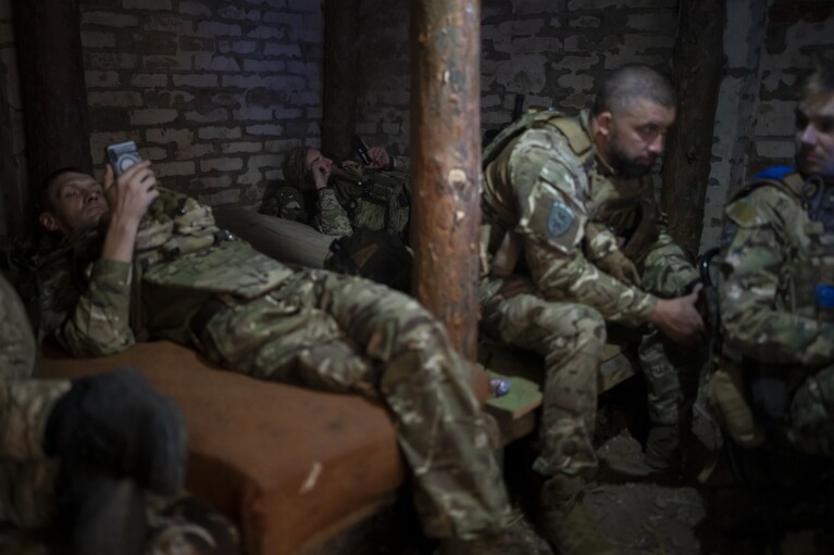 Ukrainian servicemen of the drone unit rest inside a basement on the front line in the outskirts of Kremmina, Ukraine, Sunday, Aug. 20, 2023. (AP Photo/Bram Janssen)