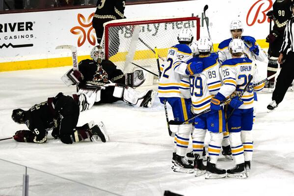 Arizona Coyotes' Christian Fischer (36) and goalie Connor Ingram (39) sit on the ice as Buffalo Sabres players celebrate their go-ahead goal in the third period during an NHL hockey game, Saturday, Dec. 17, 2022, in Tempe, Ariz. Buffalo Sabres won 5-2 over the Arizona Coyotes. (AP Photo/Darryl Webb)