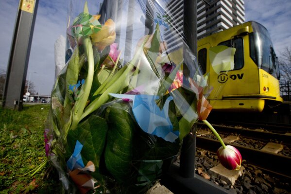 
              A tram passes flowers placed at the site of a shooting incident on a tram, in Utrecht, Netherlands, Tuesday, March 19, 2019. Dutch police and prosecutors pressed on Tuesday with their investigation into the motive of a suspect who they believe shot and killed three people and injured five more in an attack on a tram in the central city of Utrecht. (AP Photo/Peter Dejong)
            