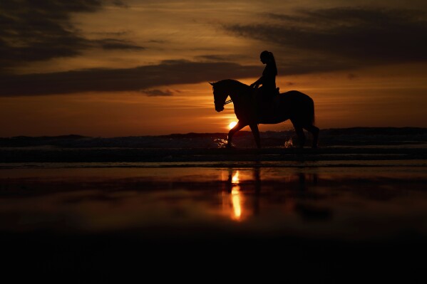 Sandra Hernandez, 23, rides her horse during sunset at Atxabiribil beach in the Penon de Sopelana, northern Spain, Tuesday, May 20, 2025. (AP Photo/Manu Fernandez)