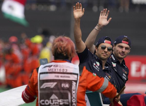 Red Bull driver Max Verstappen, of the Netherlands, right, and teammate Sergio Perez, of Mexico, wave to the crowd during a parade prior to the Formula One Mexico Grand Prix auto race at the Hermanos Rodriguez racetrack in Mexico City, Sunday, Oct. 30, 2022. (AP Photo/Fernando Llano)