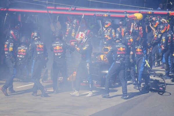 Red Bull driver Max Verstappen of the Netherlands walks from his car as his mechanics work to put out a fire during the Australian Formula One Grand Prix at Albert Park, in Melbourne, Australia, Sunday, March 24, 2024. (AP Photo/Scott Barbour,Pool)