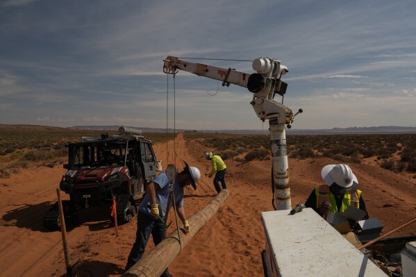 A crew lifts a power line pole during construction at a home, Tuesday, Oct. 8, 2024, on the Navajo Nation in Halchita, Utah. (AP Photo/Joshua A. Bickel)