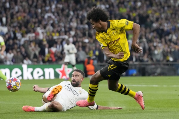 Dortmund's Karim Adeyemi, attempts a shot at goal past Real Madrid's Dani Carvajal, on the ground, during the Champions League final soccer match between Borussia Dortmund and Real Madrid at Wembley stadium in London, Sunday, June 2, 2024. (AP Photo/Frank Augstein)