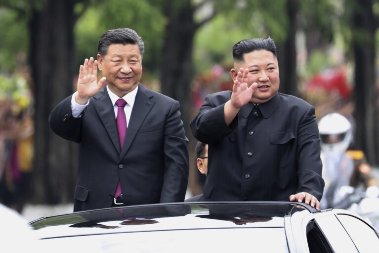 FILE - In this June 20, 2019, file photo released by China's Xinhua News Agency, visiting Chinese President Xi Jinping, left, and North Korean leader Kim Jong Un wave from an open top limousine as they travel along a street in Pyongyang, North Korea. China appears to be keeping its distance as Russia and North Korea move closer to each other with a new defense pact that could tilt the balance of power between the three authoritarian states.(Ju Peng/Xinhua via AP, File)
