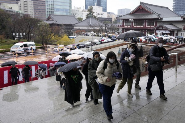 People arrive in the rain to attend the 