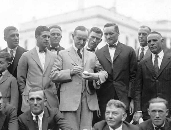 President Calvin Coolidge signs a baseball for Hall of Fame pitcher Walter Johnson as other members of the Senators look on in 1924. (Library of Congress via AP)