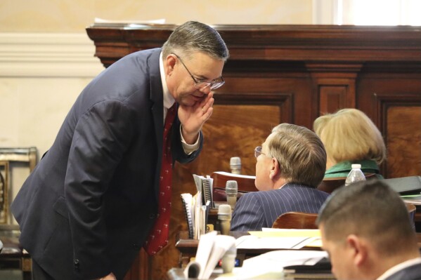 Republican South Carolina state Rep. John McCravy speaks with a colleague during a debate on gender-affirming care for minors , Wednesday, Jan. 17, 2024 in Columbia, S.C. The Republican-dominated South Carolina House is considering a bill that would bar health professionals from performing gender-transition surgeries, prescribing puberty-blocking drugs and overseeing hormone treatments for patients under 18 years old. (AP Photo/James Pollard)