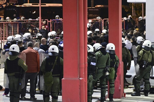 Riot police detain dozens of fans outside the Melina Merkouri indoor stadium, in western Athens, early Friday, Dec. 8, 2023. A Greek policeman has been severely injured as a mob of volleyball fans poured out of an Athens arena and attacked riot police. A flare shot by a fan severed an artery in the thigh of the 30-year-old officer Thursday night. (Yorgos Matthaios/Eurokinissi Sports via AP)