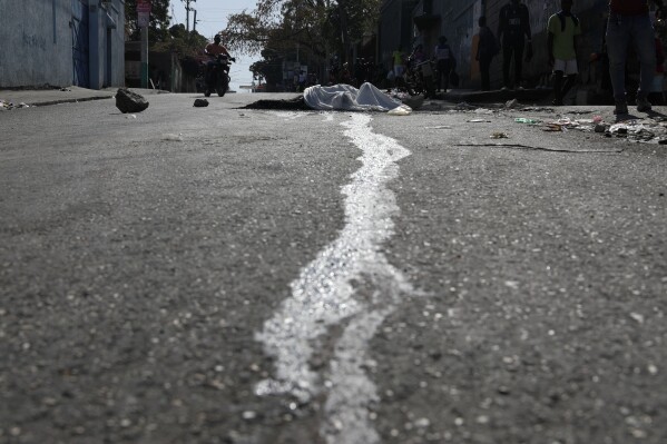 Blood streams from a body lying in the street in the Petion-ville area of Port-au-Prince, Haiti, Wednesday, March 20, 2024. (AP Photo/Odelyn Joseph)