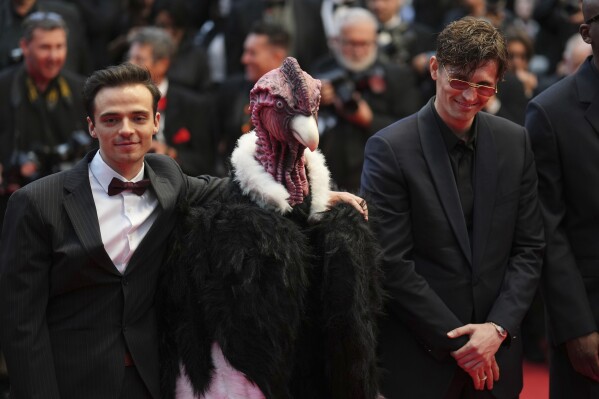Raphael Quenard, left, and Hugo David, right, pose with a person dressed in bird costume upon arrival at the premiere of the film 'Die, My Love' at the 78th international film festival, Cannes, southern France, Saturday, May 17, 2025. (Photo by Lewis Joly/Invision/AP)