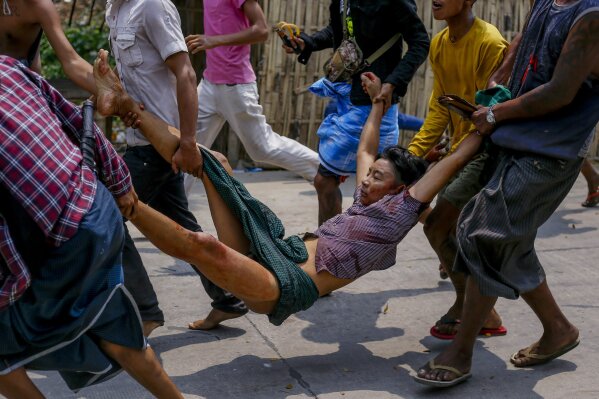 Manifestantes contrarios al golpe de Estado cargan a un hombre herido el domingo 14 de marzo de 2021 tras choques con policías y soldados, en Yangón, Myanmar. (AP Foto)
