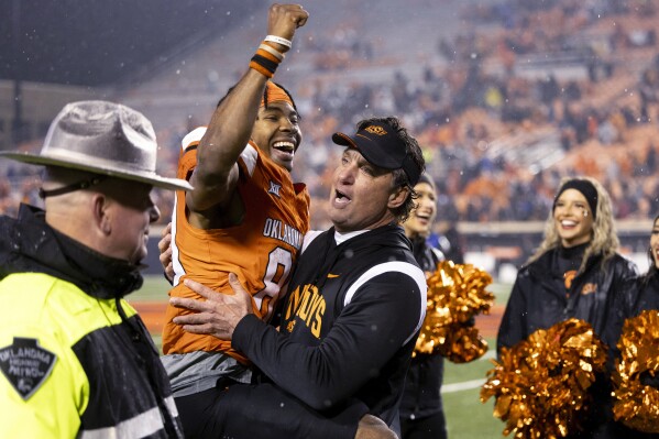 Oklahoma State wide receiver Brennan Presley (80) celebrates in the arms of Oklahoma State coach Mike Gundy arms after an NCAA college football game against BYU on Saturday, Nov. 25, 2023, in Stillwater, Okla. (AP Photo/Mitch Alcala)