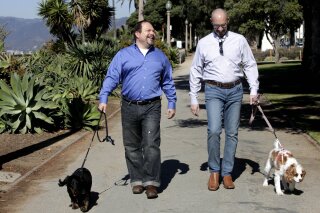 
              FILE - In this Feb. 23, 2012, file photo, Steven May, right, walks with his dog, Winnie beside his attorney, David Pisarra, with his dog, Dudley in Santa Monica, Calif. California courts could be going to the dogs, and maybe the cats too, under a new law signed by Gov. Jerry Brown. The law, signed Thursday, Sept. 28, 2018, gives judges the discretion of applying rules similar to those in child-custody cases when determining who gets the family pet following a divorce. It takes effect Jan. 1, 2019. (AP Photo/Nick Ut, File)
            