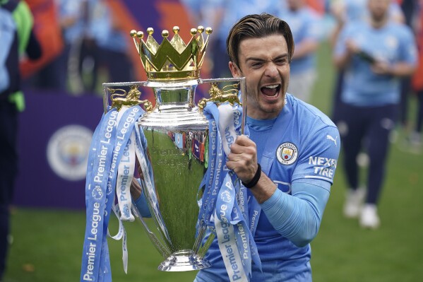FILE - Manchester City's Jack Grealish celebrates with the trophy after winning the 2022 English Premier League title at the Etihad Stadium in Manchester, England, Sunday, May 22, 2022. The Premier League fears a new “banking-style” soccer regulator could damage the competitiveness of the world's most popular league. The league's chief executive Richard Masters has also raised concerns that proposed measures would impact its value and deter investment into a competition that earns billions of dollars through the sale of broadcast rights across the globe. (AP Photo/Dave Thompson, File)