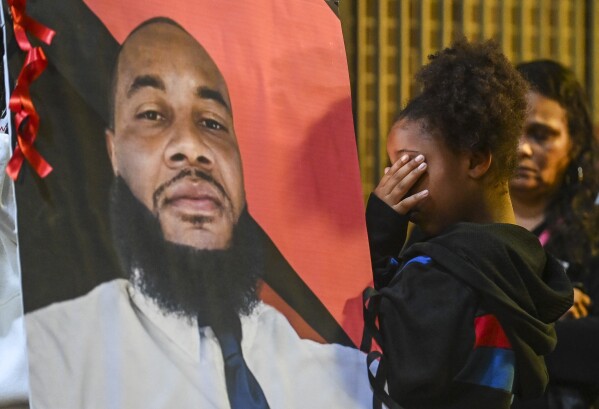 A girl prays for Stephen Perkins during a vigil outside Decatur, Ala. City Hall/Police Department, Thursday, Oct. 5, 2023. Police shot and killed Perkins, 39, the week before in what began in an early morning confrontation with a tow truck driver trying to repossess a vehicle, police said. Perkins' family said that he was not behind on payments and the vehicle should not have been repossessed. (Jeronimo Nisa/The Decatur Daily via AP)