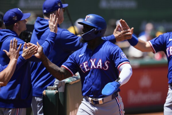 Texas Rangers' Adolis García, center, celebrates with teammates at the dugout after scoring against the Oakland Athletics on Jonah Heim's single during the second inning of a baseball game Tuesday, May 7, 2024, in Oakland, Calif. (AP Photo/Godofredo A. Vásquez)