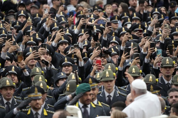 Finance Police officers film and salute Pope Francis as he arrives for his weekly general audience in St. Peter's Square, at the Vatican, Wednesday, Oct. 25, 2023. (AP Photo/Gregorio Borgia)