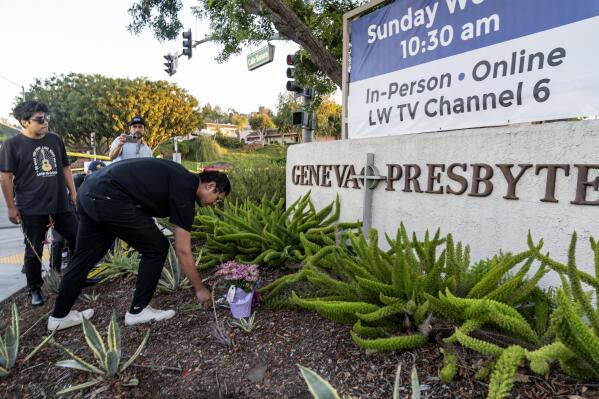Hector Gomez, left, and Jordi Poblete, worship leaders at the Mariners Church Irvine, leave flowers outside the Geneva Presbyterian Church in Laguna Woods, Calif., Sunday, May 15, 2022, after a fatal shooting. (AP Photo/Damian Dovarganes)