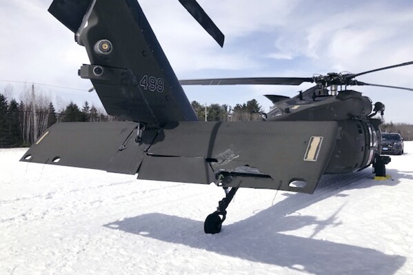 In this U.S. Army photograph by attorney Douglas Desjardins, a damaged Black Hawk helicopter rests on the snow, March 13, 2019, in Worthington, Mass. A Massachusetts man wants the government to pay nearly $10 million after being badly injured in a crash with a Black Hawk helicopter. The lawsuit filed by Jeffrey Smith against the government follows a 2019 crash in which Smith's snowmobile collided with the helicopter that was parked on a trail at dusk. (U.S. Army photograph provided by attorney Douglas Desjardins via AP)
